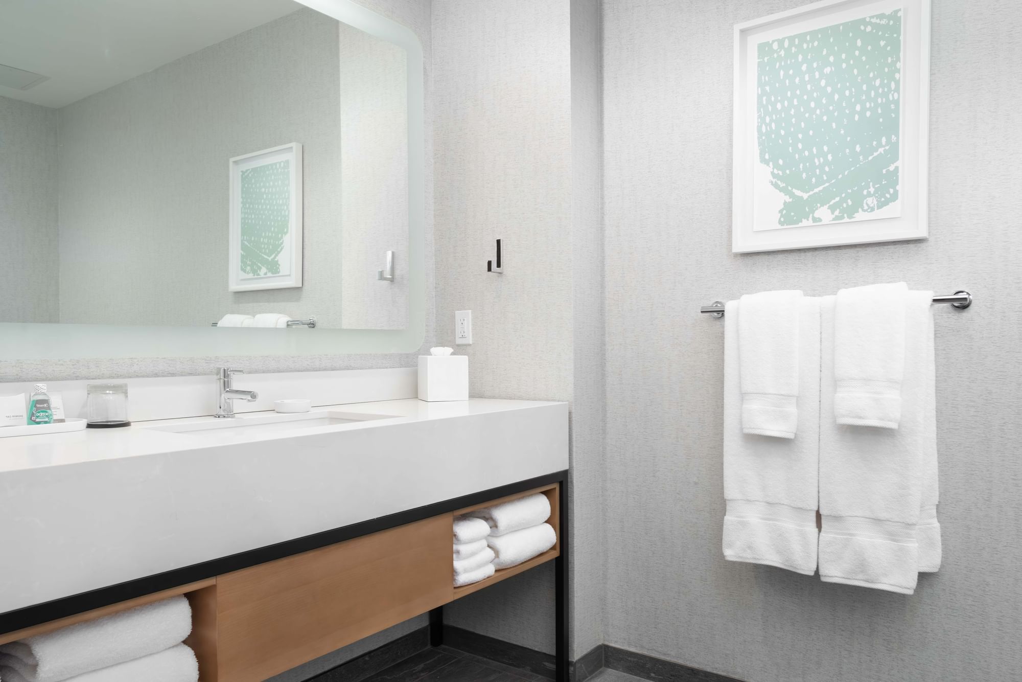 A clean and modern bathroom with a large sink, mirror, and towels.