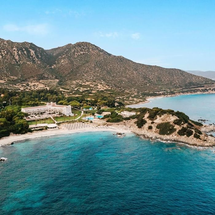 Aerial view of Falkensteiner Resort Capo Boi with beach loungers & hills