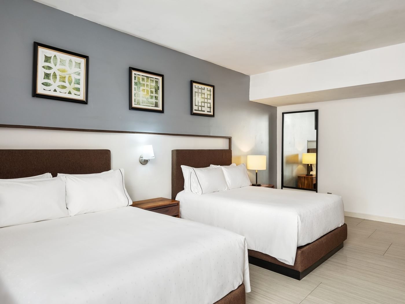 Penthouse Luxury with two brown-base cozy beds, grey walls, and framed geometric wall arts at Sunvivia Mazatlán