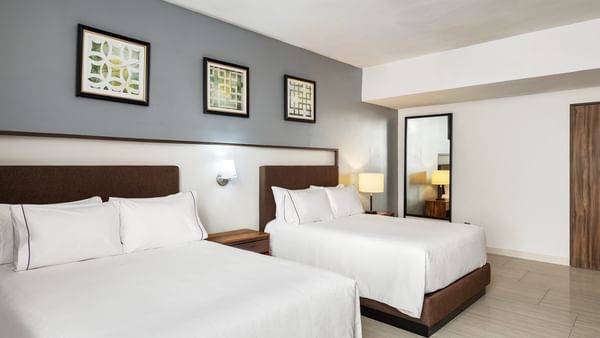 Penthouse Luxury with two brown-base cozy beds, grey walls, and framed geometric wall arts at Sunvivia Mazatlán