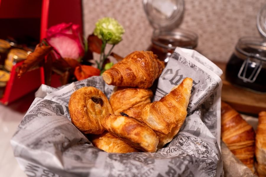 Corbeille de croissants et de viennoiseries frais, agrémentée de fleurs, au restaurant Le W de l'hôtel Warwick Paris Champs-Élysées