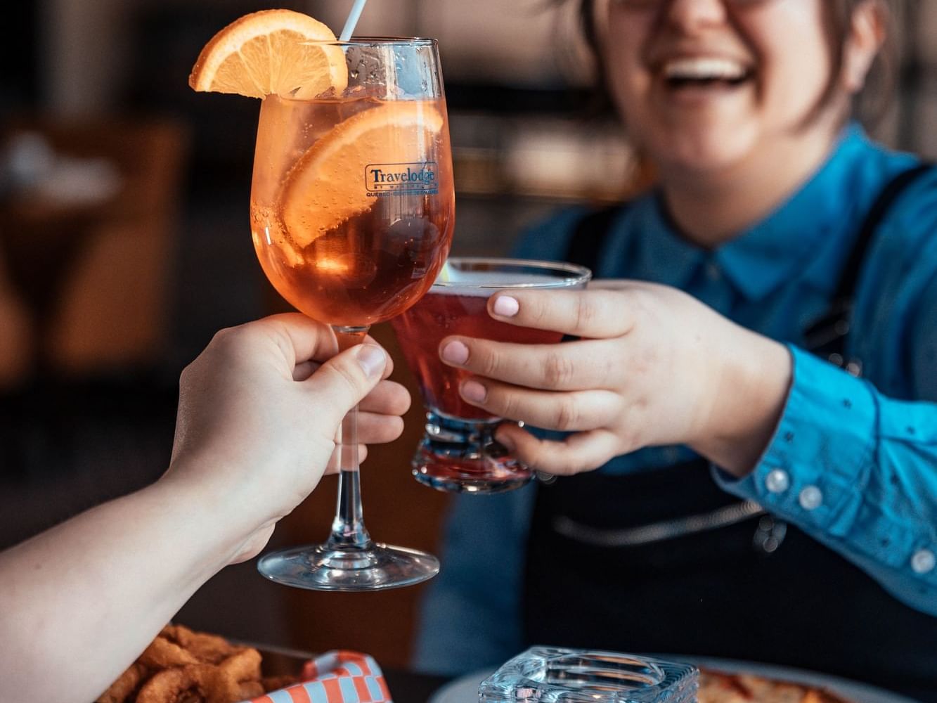 Two people toasting Aperol Spritz in Jules-Verne Restaurant at Travelodge Hotel & Convention Center Québec City