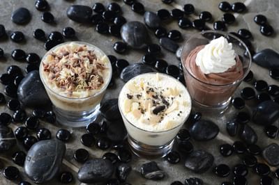 Three dessert shooters artfully surrounded by black pebbles