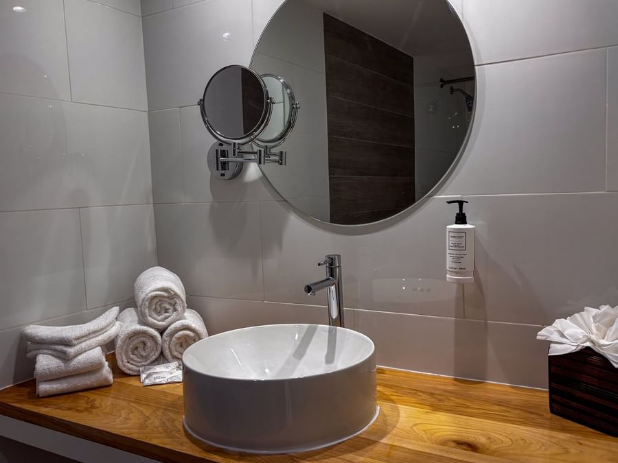 Vessel sink on a wood counter by rolled towels and a round mirror in Island View at Warwick Paradise Island Bahamas