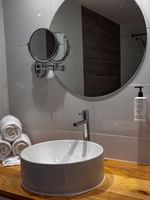 Vessel sink on a wood counter by rolled towels and a round mirror in Island View at Warwick Paradise Island Bahamas