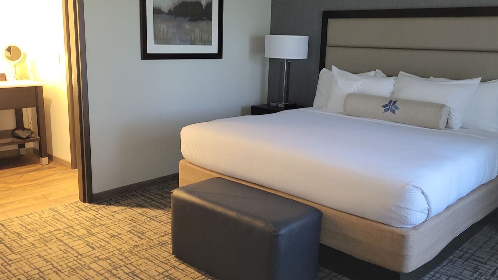 King size bed with a leather ottoman and a bedside lamp in corner suite at Shangri-La Monkey Island 