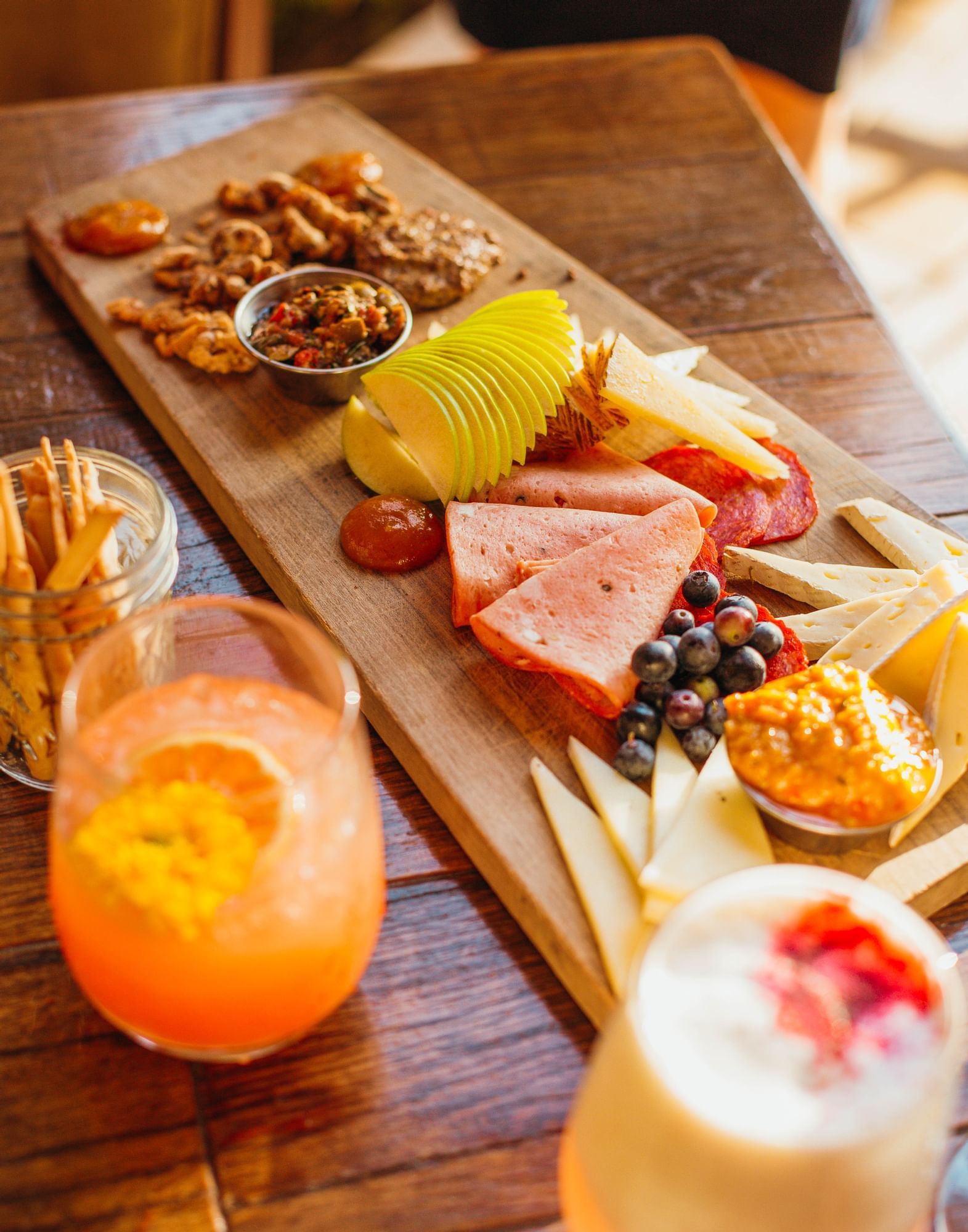 Lorem ipsum Charcuterie tray with fruit, meat nuts and cheese next to two cocktails