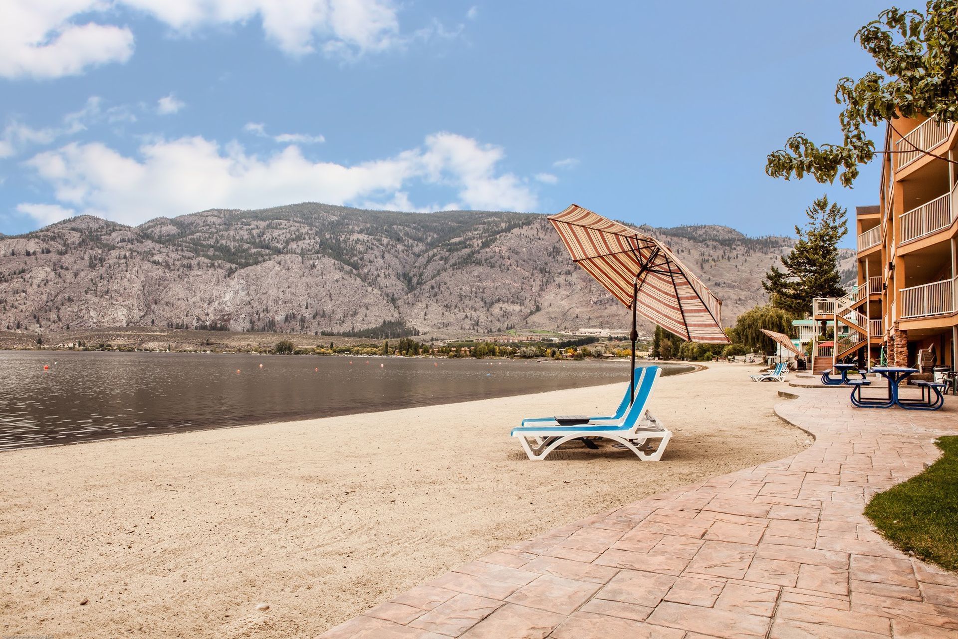 Chairs and umbrellas on beach overlooking lake and mountains
