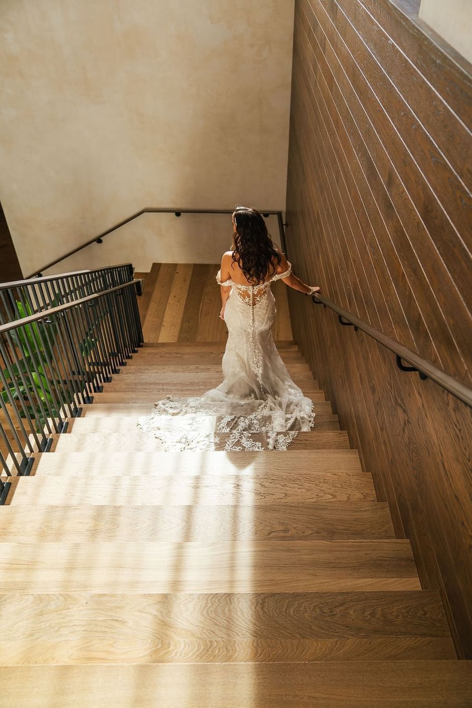 Woman in a wedding dress descending a sunlit wooden staircase in The Study at University of Chicago