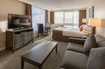 One bedroom Suite with a comfortable king sized bed, a couch and an armchair at Embassy Inn Victoria