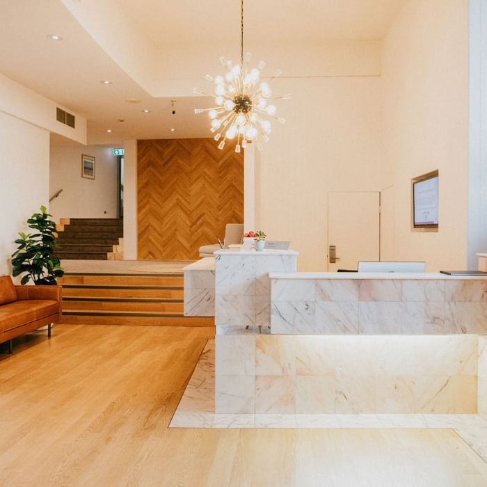 Elegant lobby with a marble reception desk, modern chandelier, and brown couch at Mercure Charlestown.
