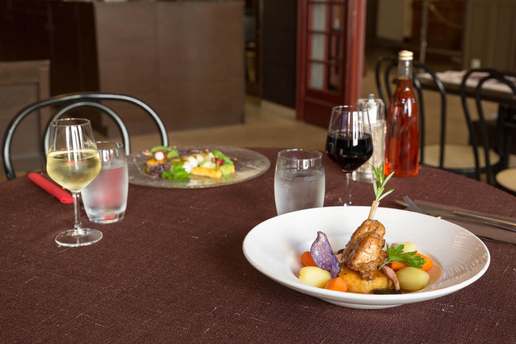 Two cooked dishes nicely plated served with two glasses of wine