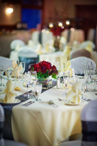 Wedding reception table with a floral centerpiece with red flowers, white tablecloth, and wine glasses at The Stanley Hotel