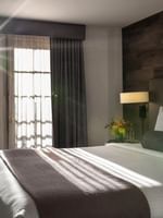 King bed by a side table under a wood-paneled wall in a sunlit room in Executive Suites at Warwick Denver