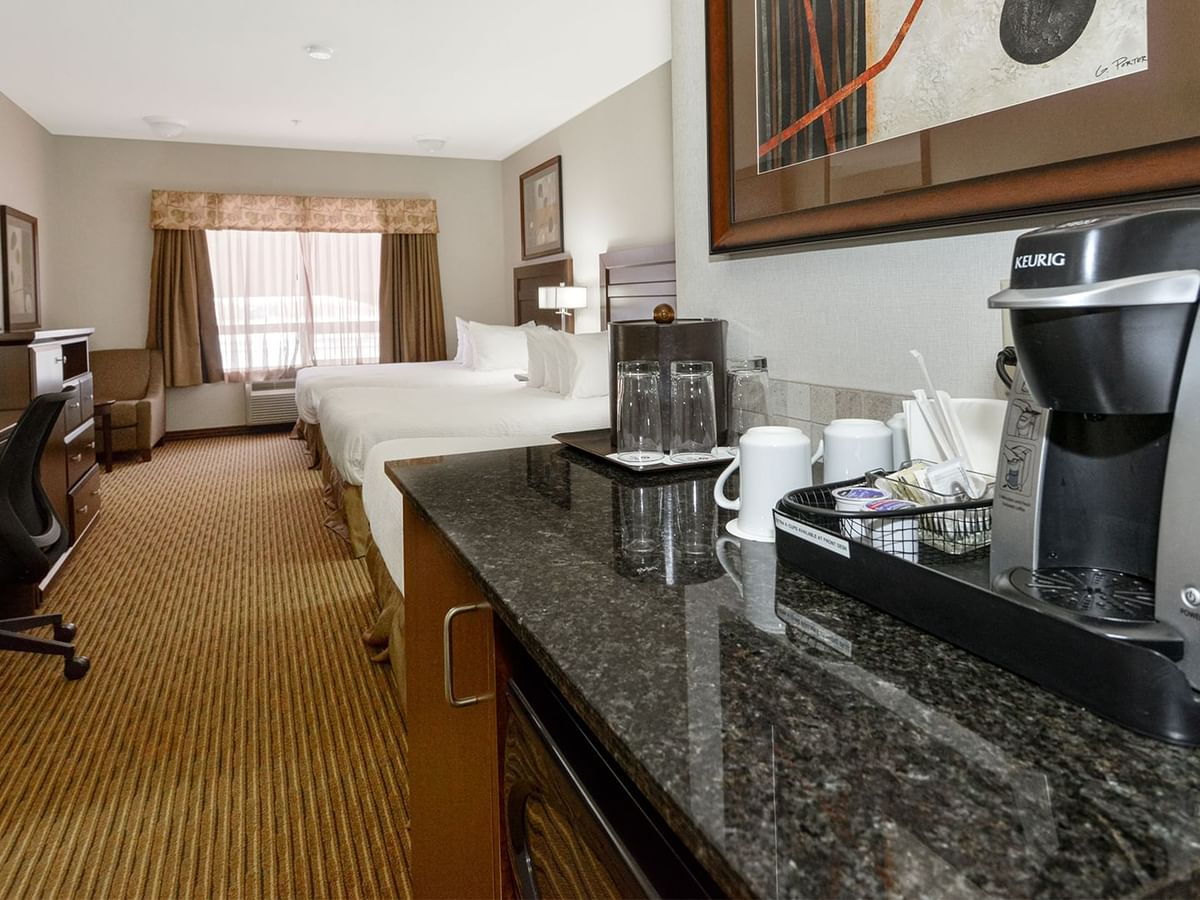 Hotel room with three queen beds, microwave, TV, work desk and coffee machine