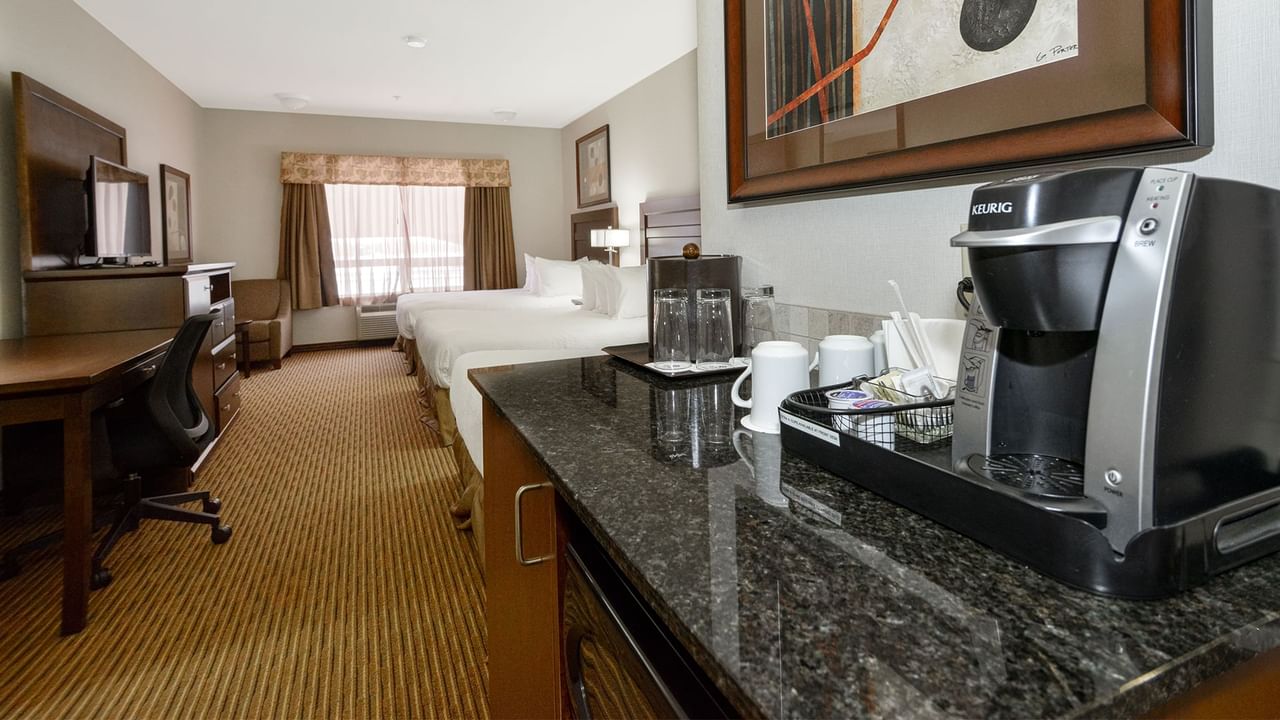 Hotel room with three queen beds, microwave, TV, work desk and coffee machine