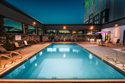 Pool area with pool chairs at night in Carriage House Hotel