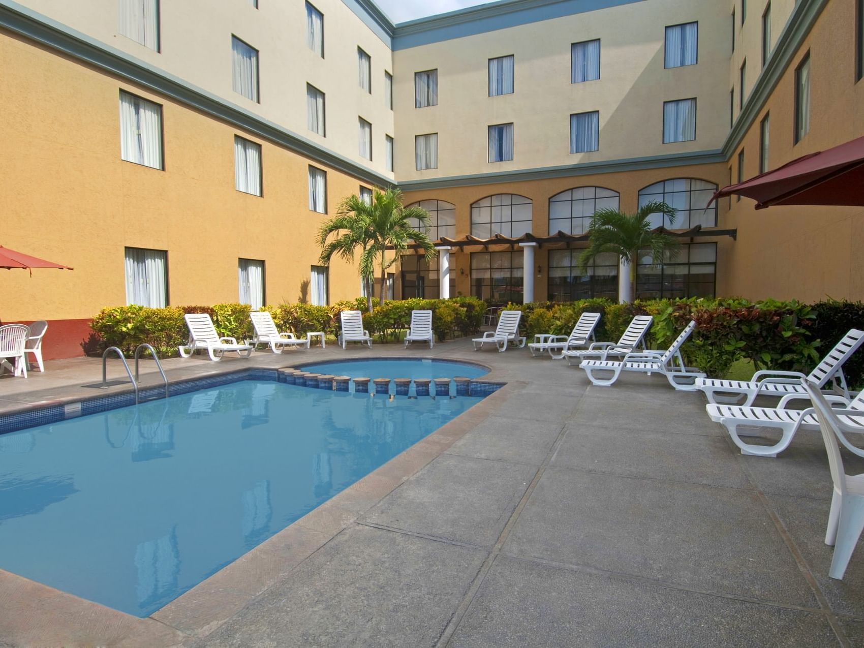 The pool area in a backyard with sunbeds at Fiesta Inn