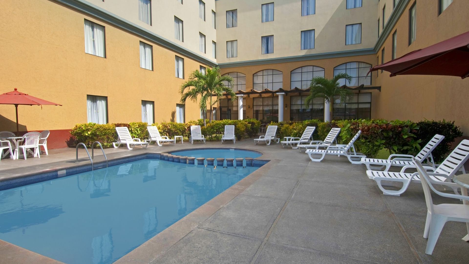 Pool beds and patio umbrellas by pool at FI Poza Rica