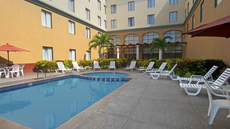 Pool beds and patio umbrellas by pool at FI Poza Rica
