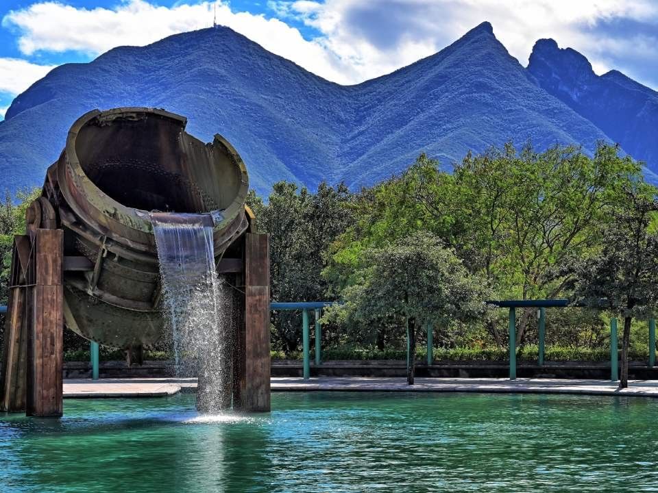 Parque Fundidora pouring water into a pool with mountain peaks near Camino Real Monterrey