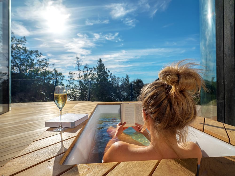 Girl in coastal Pavilion Bay outdoor bathtub at Freycinet Lodge