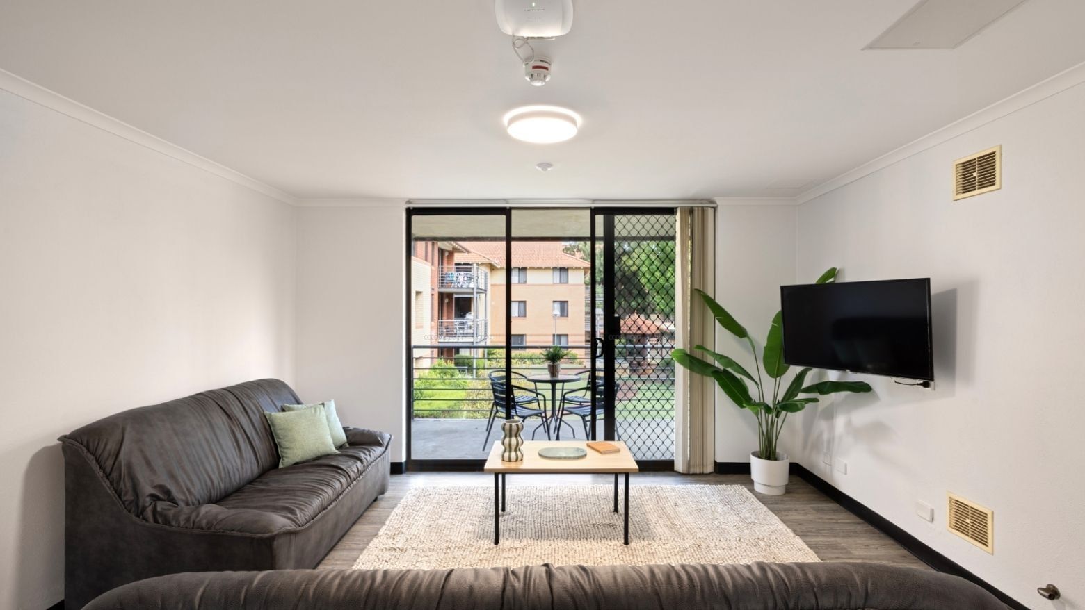 Cozy living room with couch, TV, and balcony at UniLodge at Curtin University - Erica Underwood House.