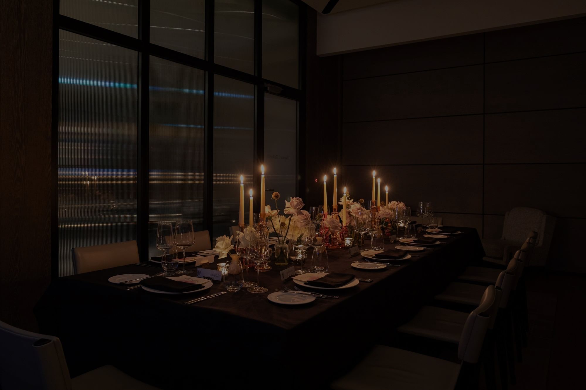Dimly lit dining table elegantly set with candles, floral arrangements, and fine tableware at The Londoner Hotel