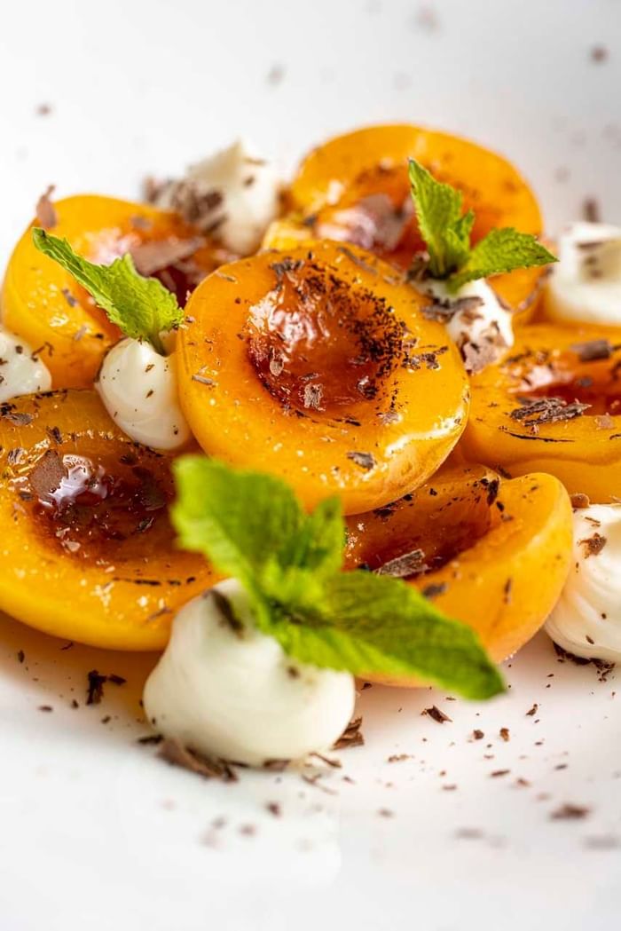 A plate of assorted fruits, cheese, & mint leaves served at EMME Restaurant