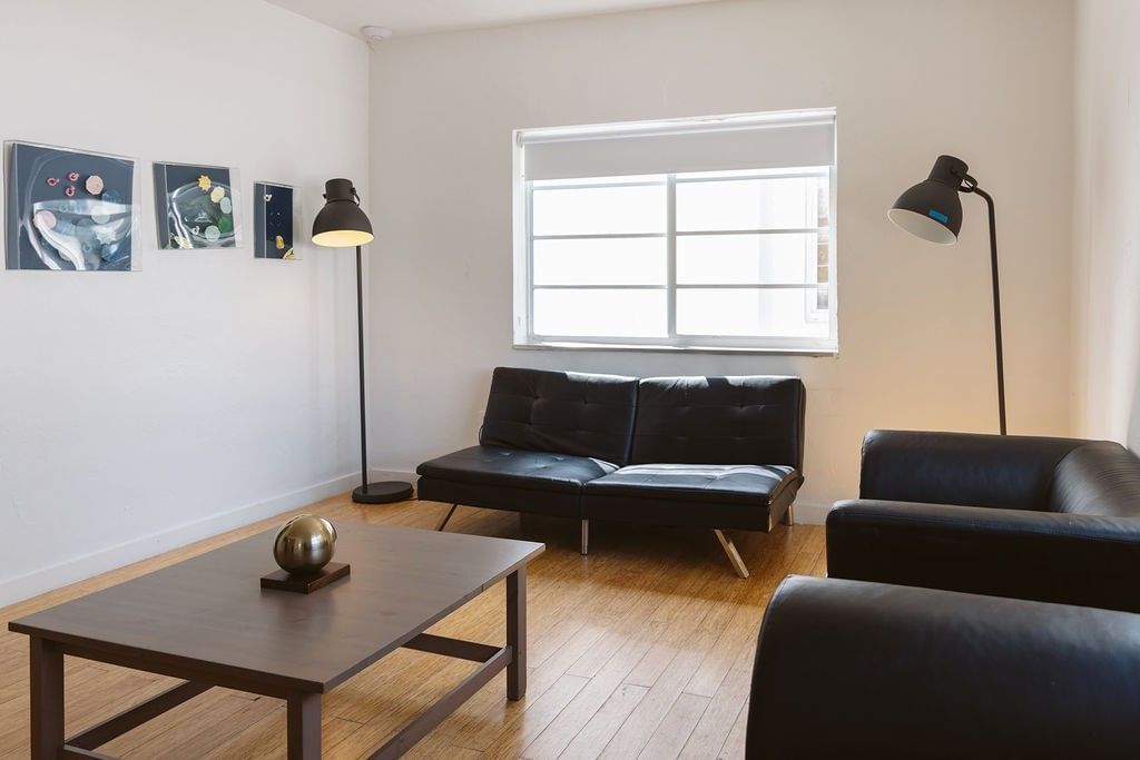 A modern lobby with a black leather sofa, coffee table, and floor lamps.