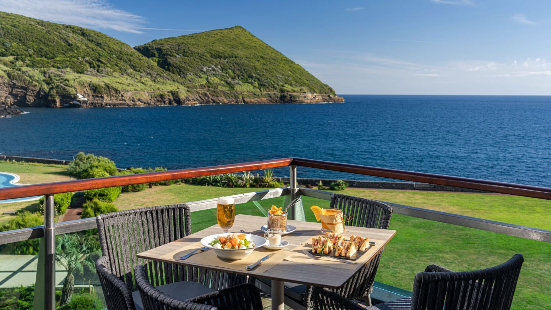 Club sandwiches and fries served with beer on a balcony area with a sea view in Fanal Bar at Terceira Mar Hotel