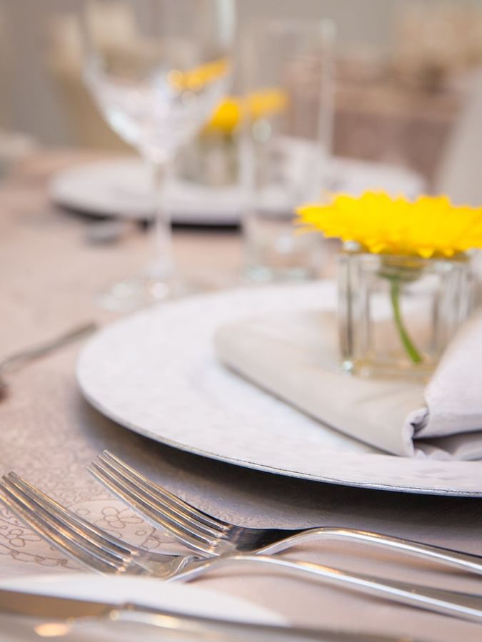 Yellow flower in a small glass vase by a folded napkin on a table in Salon René-Lévesque at Warwick Le Crystal Montreal