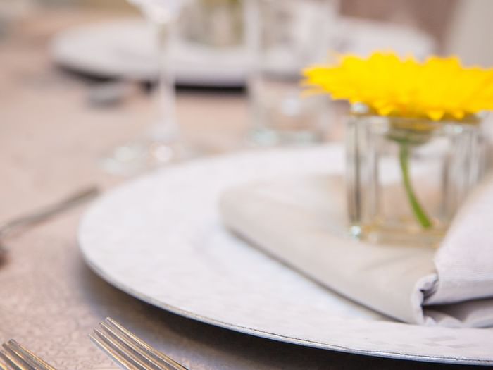 Yellow flower in a small glass vase by a folded napkin on a table in Salon René-Lévesque at Warwick Le Crystal Montreal