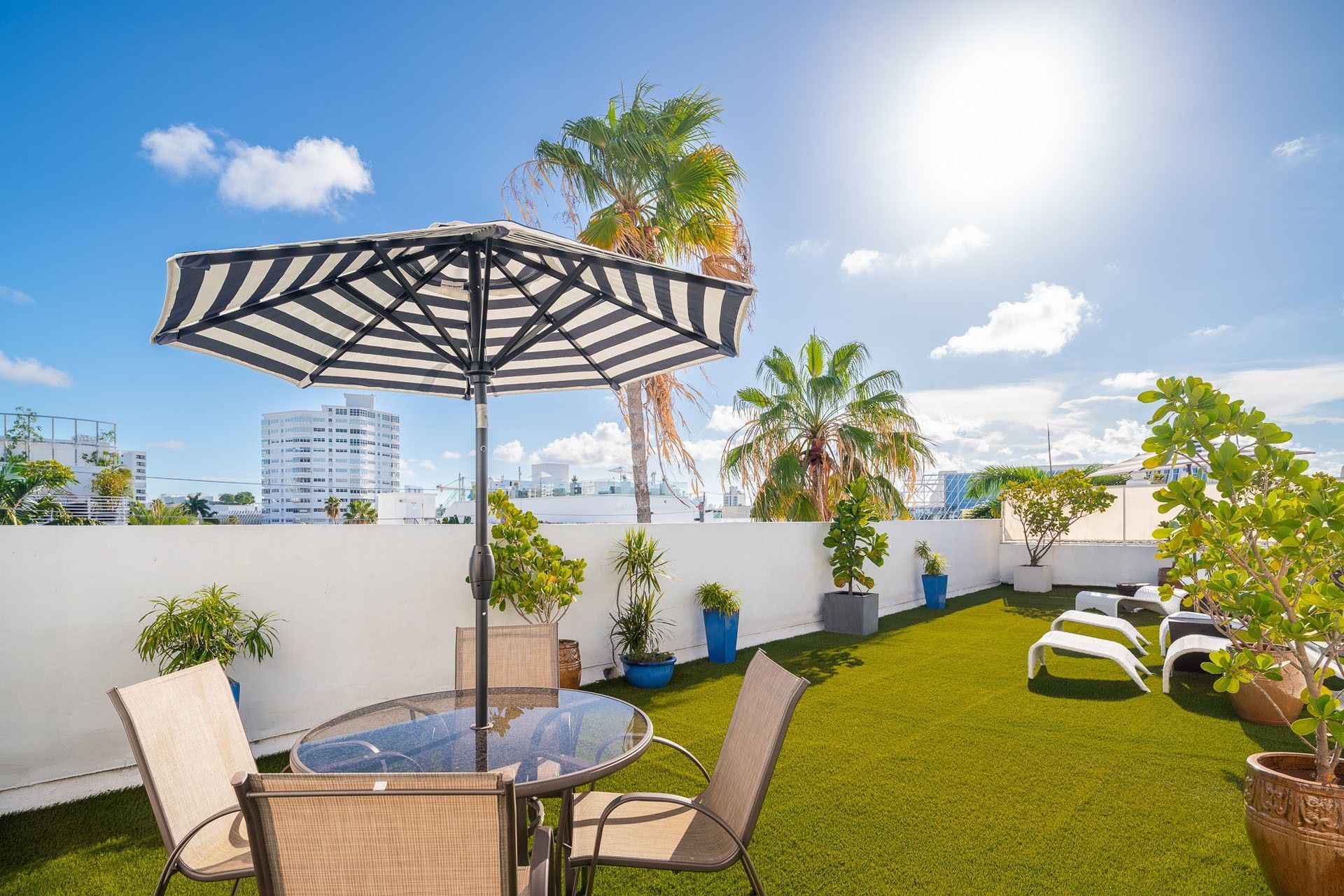 A rooftop lounge with artificial turf, outdoor furniture, and potted plants.