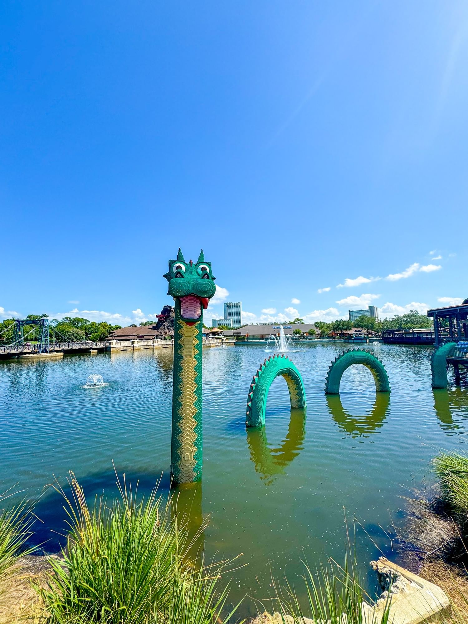 A large green sea monster made of LEGOs emerges from a body of water at Disney Springs.