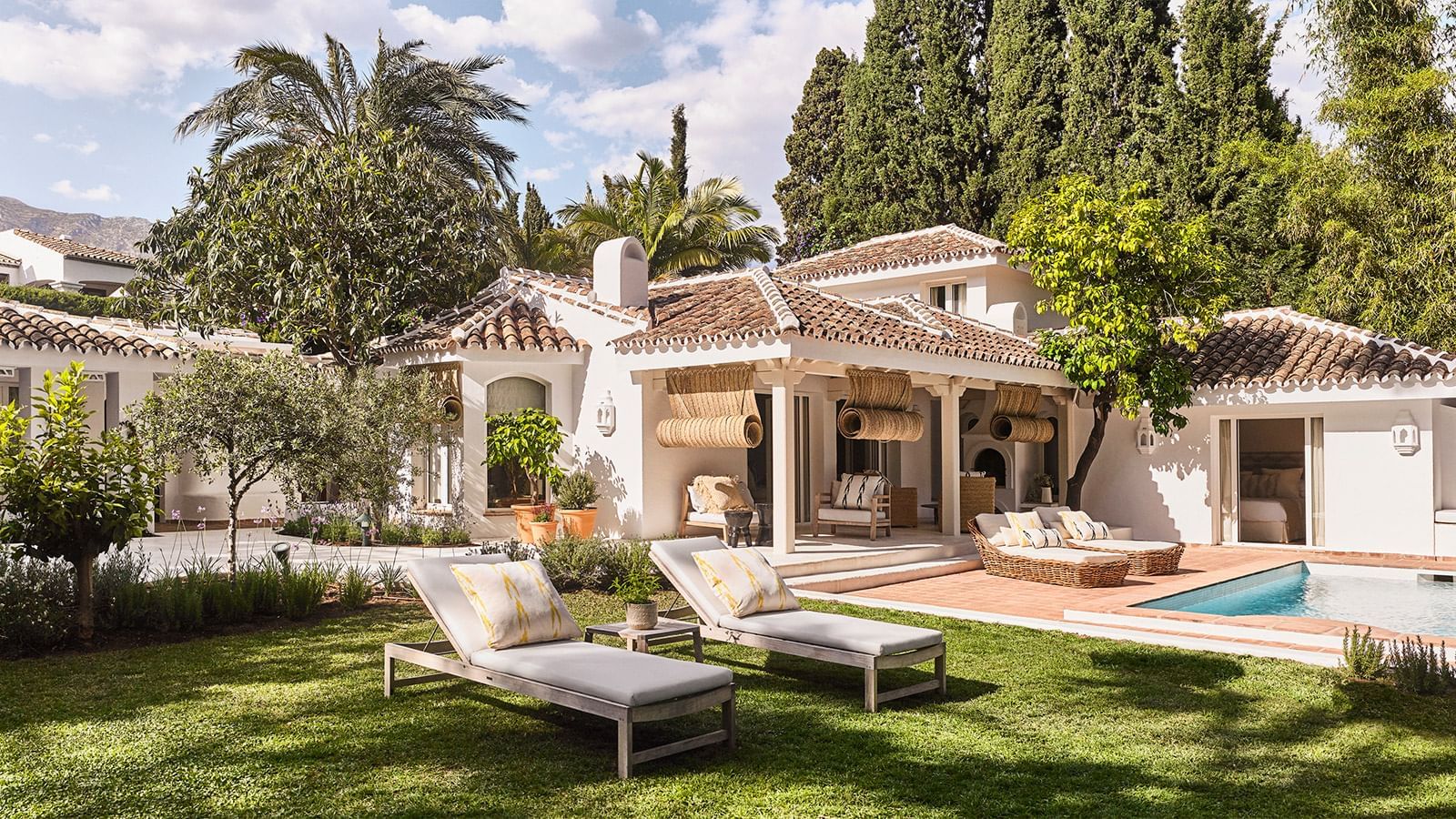 Villa exterior with lounge chairs placed on a lawn by the pool and a covered patio at the Marbella Club