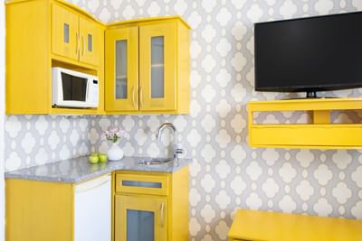 Kitchenette with appliances & TV on wall shelf in Queen Premiere Sunset at Retro Suites Hotel