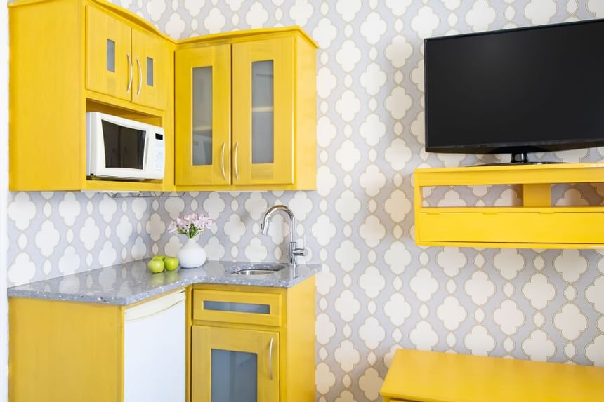 a bright yellow kitchenette with decorative wall paper and a wal