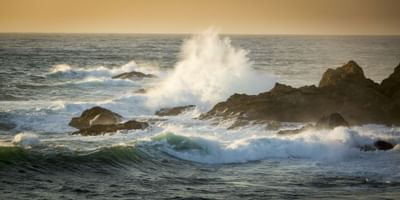 Waves crashing onto rocks on a beach at Heritage House Resort