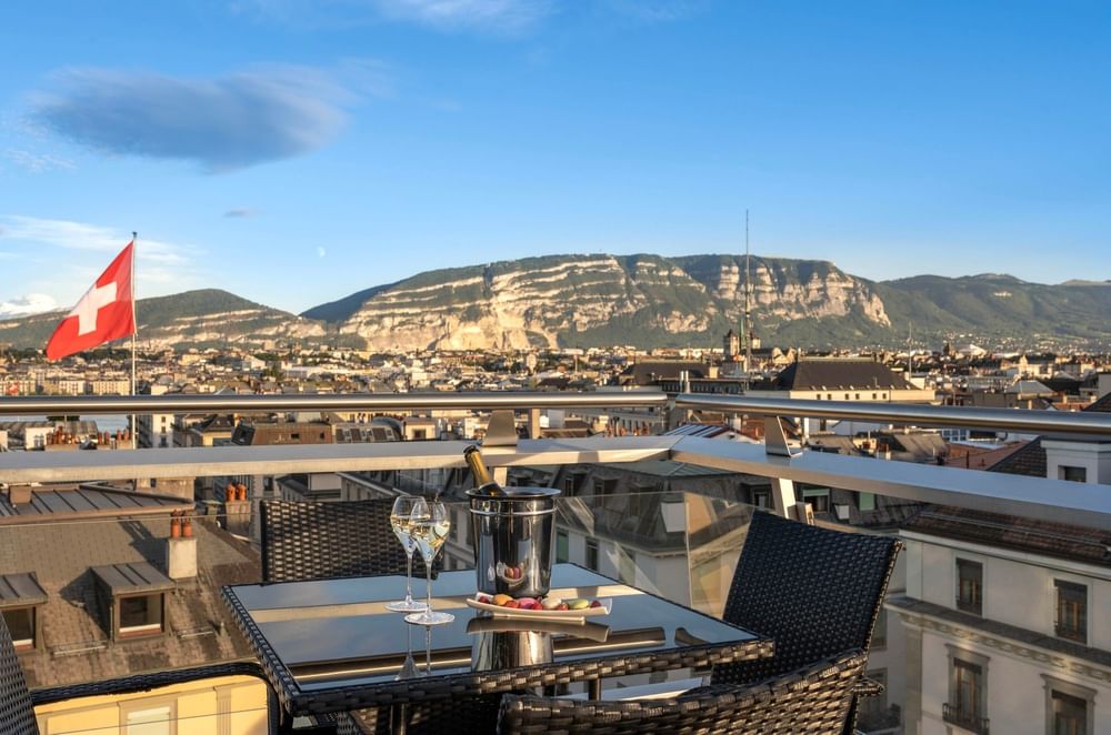 Bistro set by a railing under a blue sky surrounding a mountain in Penthouse Terrace Suite at Warwick Geneva