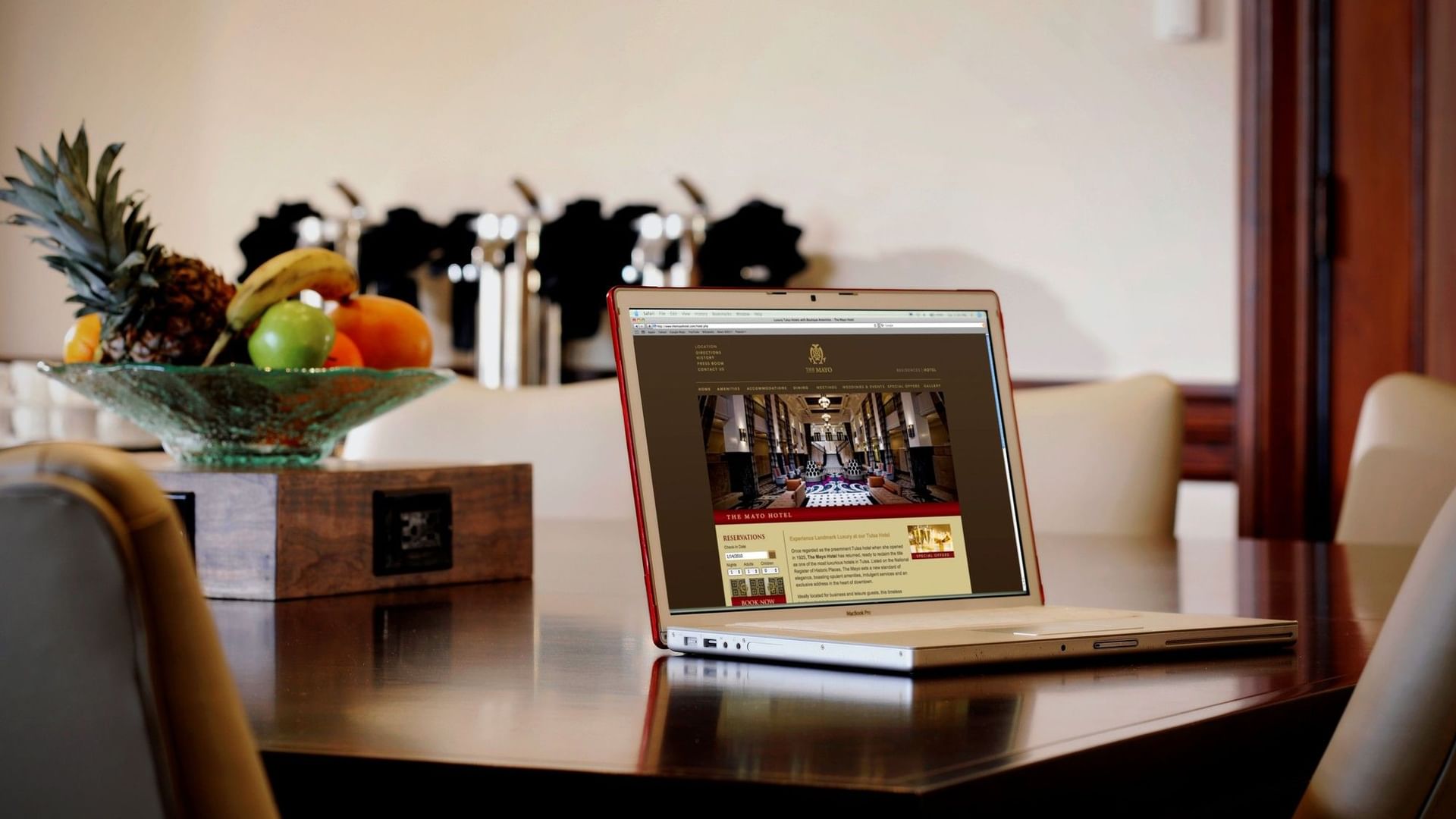 Laptop on a wooden table with fruit bowl at The Mayo Hotel in Tulsa.