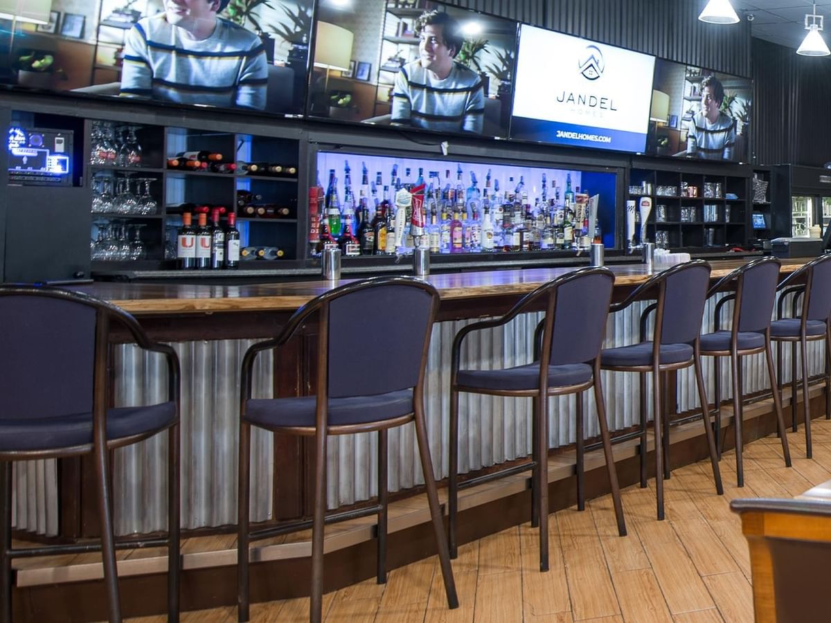 Row of blue cushioned bar stools at The Den Pub counter.