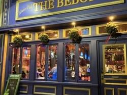 The Bebop restaurant's blue facade with lit windows, potted plants, and a chalkboard sign outside.