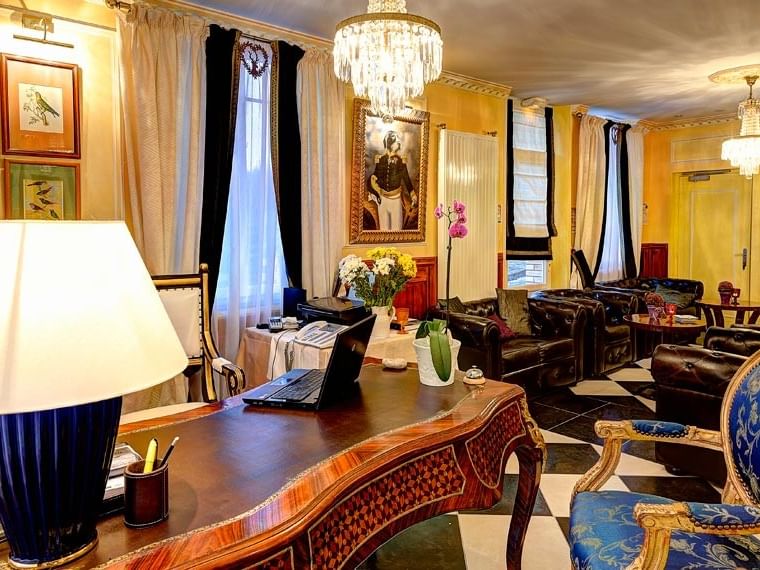 Salon élégant avec fauteuils en cuir, lustres et bureau à Hôtel Villa Aultia.