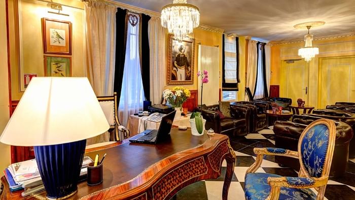 Salon élégant avec fauteuils en cuir, lustres et bureau à Hôtel Villa Aultia.