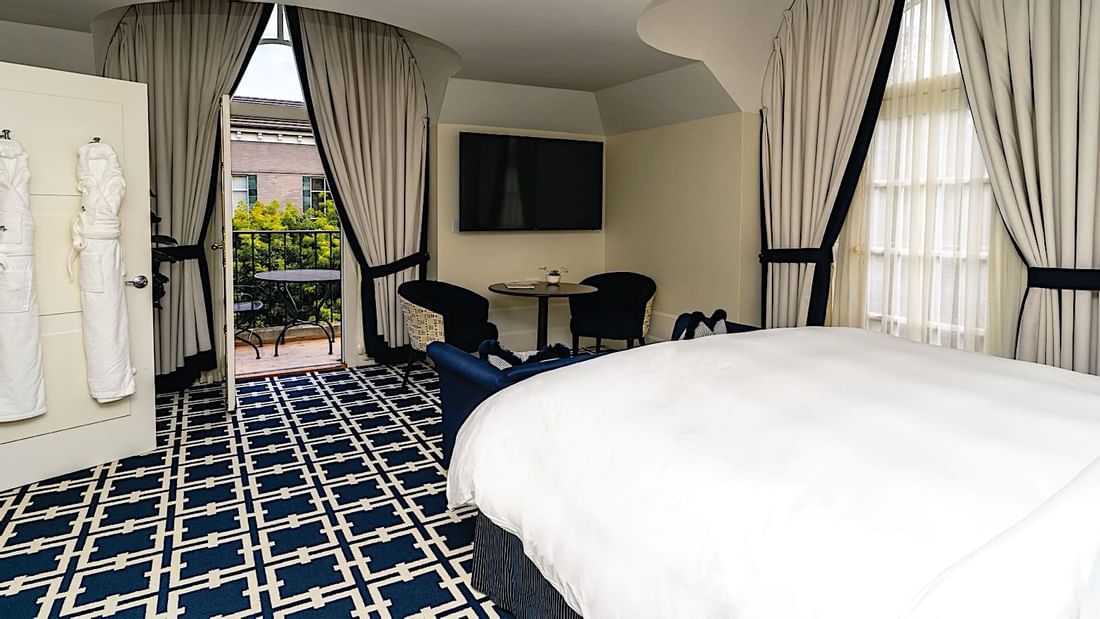 TV and seating area facing the cozy bed in Grand Deluxe Suite with a balcony at El Prado Hotel