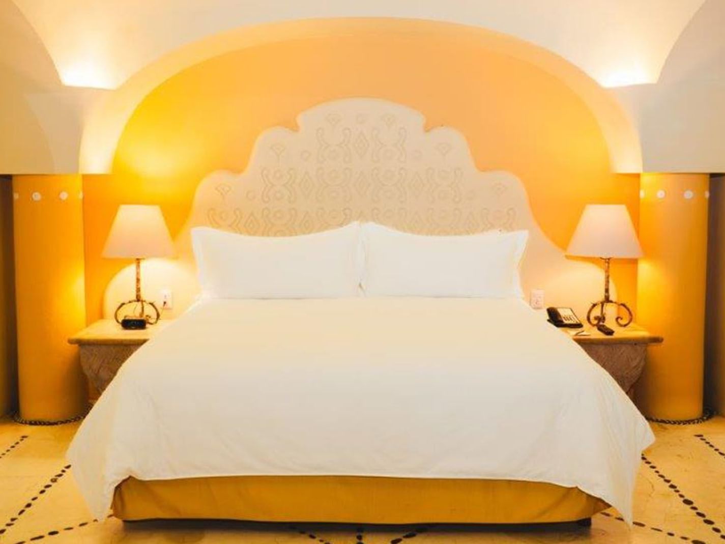 King Grand Class Suite with an arched ceiling, golden walls, and soft ambient lamp lighting at Quinta Real Huatulco