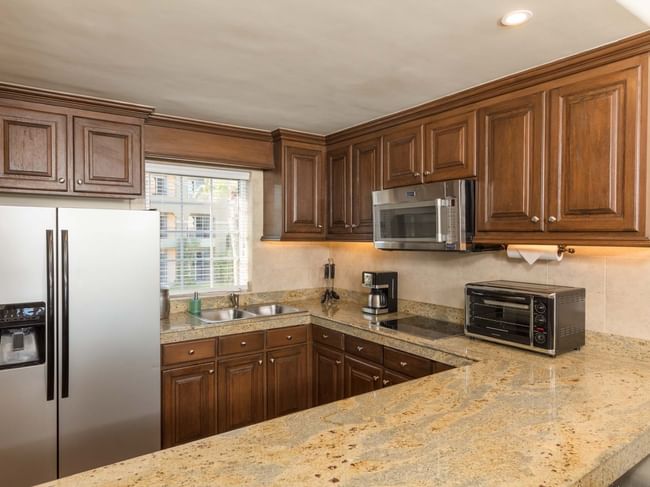 Spacious kitchen with stainless fridge and wood cabinetry in the Two Bedroom Villa at Hacienda Del Mar Los Cabos.