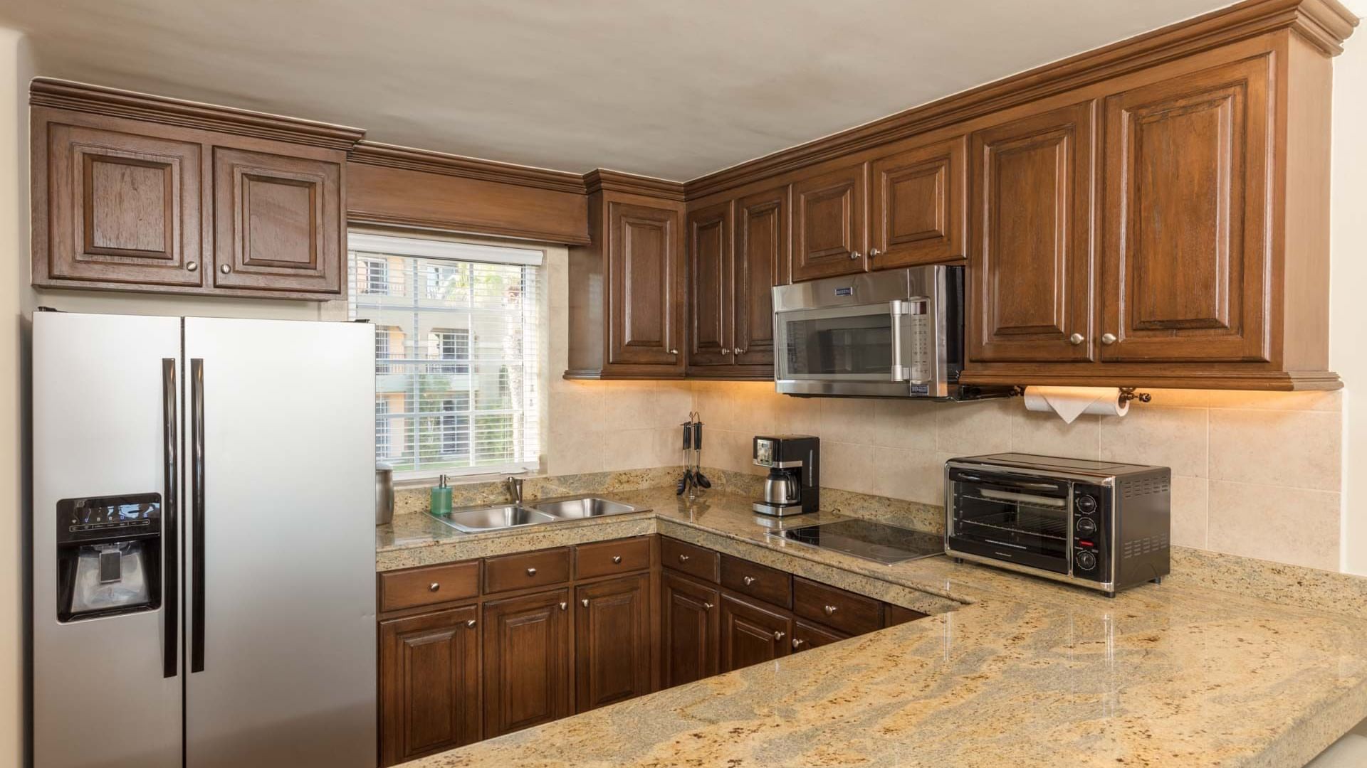 Spacious kitchen with stainless fridge and wood cabinetry in the Two Bedroom Villa at Hacienda Del Mar Los Cabos.