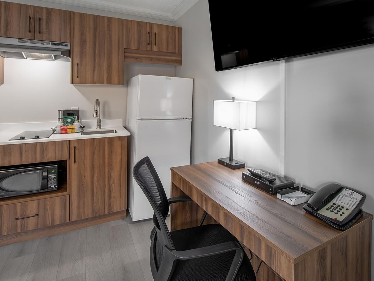 Two queen beds room with kitchenette, desk, TV, and chair.